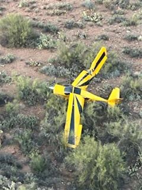 arial view of crashed yellow and black single engine plane in wilderness